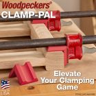 Close-up photograph showing two pipe clamps being supported by Clamp-Pals on a white oak leg assembly glue-up.
